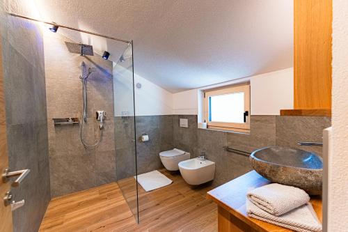 a bathroom with a sink and a glass shower at AurAlpin Apartments in Cadipietra