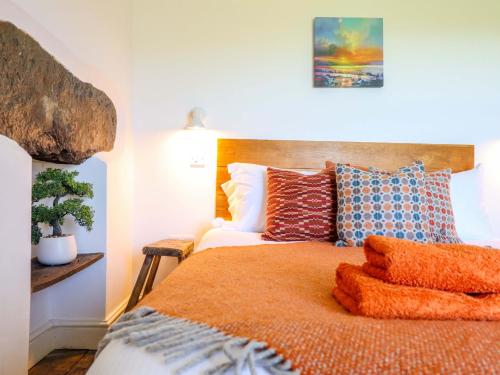 a bedroom with a bed with orange sheets and pillows at Cefn Nannau in Corwen