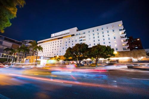 a building with cars driving past a street at night at Hotel Intercontinental Cali by IHG in Cali