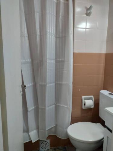 a bathroom with a toilet and a white shower curtain at Luminoso monoambiente con cochera propia dentro del edificio in La Plata