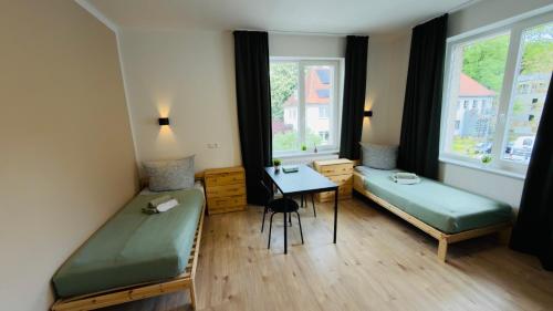 a room with two beds and a desk and a window at Aparthotel Grünewald in Hannover
