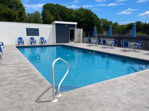 a large swimming pool with blue chairs and umbrellas at Gilford Beachfront Stay, Pool, WiFi & Parking Incl in Laconia