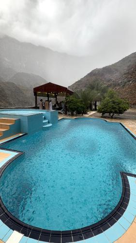 a large pool of blue water with a gazebo at Tilal Al-Qattara in Mashūq