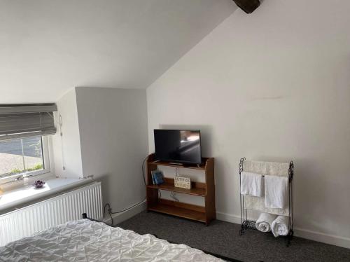 a bedroom with a bed and a tv and a window at Rhos cottage Ruthin in Ruthin
