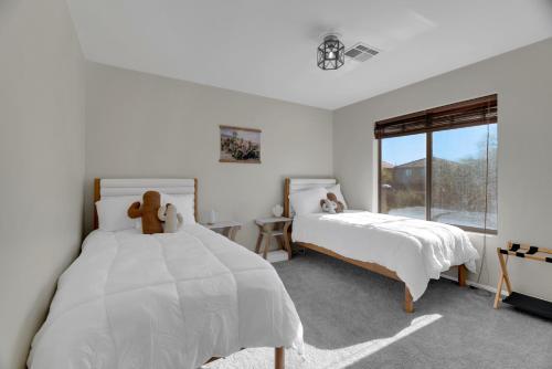 a white bedroom with two beds and a window at Cactus Retreat Pool Fire Pit Pet Friendly in Green Valley