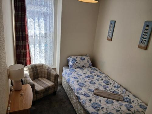 a small bedroom with a bed and a chair at 52 Cambrian St in Aberystwyth