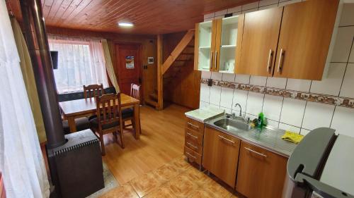 a kitchen with a sink and a table in a room at Cabañas Ohiggins in Dalcahue