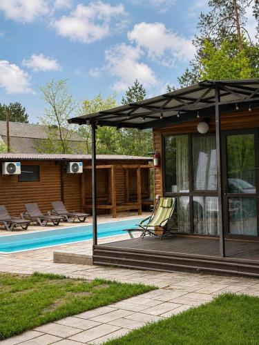 a house with a swimming pool and a patio at Joy WoodRest in Voropayev