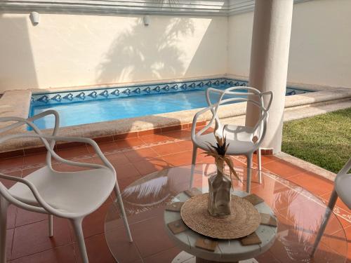 two chairs and a vase on a table next to a pool at Casa con alberca privada 3BR Ideal para familias y grupos Hasta 9 personas in Cancún