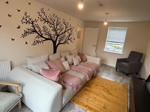 a living room with a couch with a tree and birds on the wall at Lion Gardens- The Space in Leyland