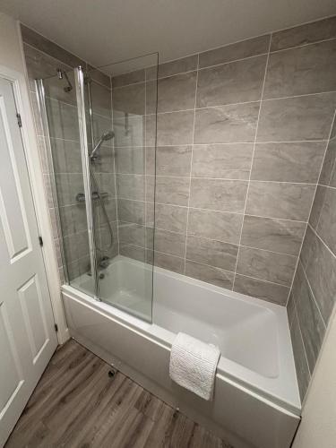 a bathroom with a tub with a glass shower at Lion Gardens- The Space in Leyland