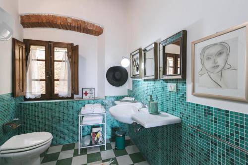 a bathroom with a sink and a toilet and green tile at Casa Marelli in Castelmuzio