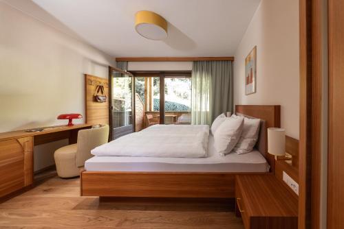a bedroom with a bed with a desk and a window at JOHAN - Rooms & Breakfast Merano in Marlengo