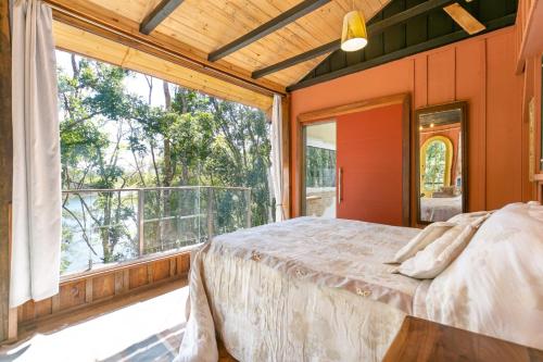 a bedroom with a bed and a large window at Cabana Paiol de Baixo in Curitiba