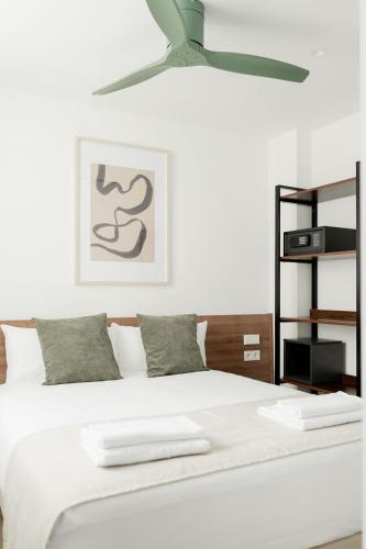 a bedroom with a white bed with a ceiling fan at SuiteStays Marino Albesa - Ayora, Valencia in Valencia