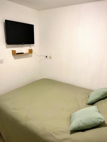 a bedroom with a bed with a flat screen tv on the wall at Studio Cosy et Moderne in Saint-Ambroix