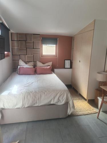 a bedroom with a large bed with pink pillows at Studio équipé proche Stade de France in Épinay-sur-Seine