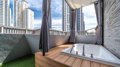 a bathroom with a bath tub on a balcony with tall buildings at The Van Stay in Busan