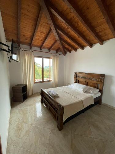 a bedroom with a large bed and a large window at Hotel Estaciones in Guatapé