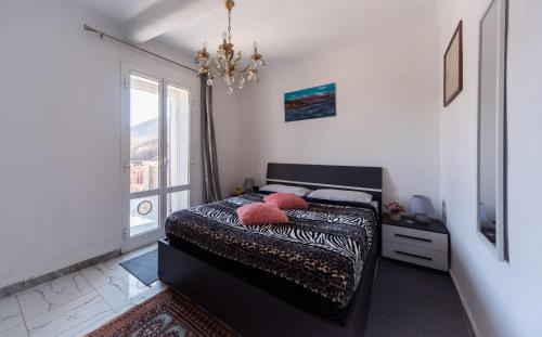 a bedroom with a bed with a chandelier and a window at zahira in Biassa