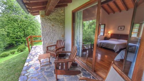 a bedroom with a bed and chairs on a porch at Hotel Palación de Toñanes in Toñanes