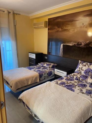 a bedroom with two beds and a painting on the wall at Relaxe La cala in Villajoyosa