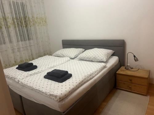 a bedroom with a bed with two black towels on it at Iris Apartment in Dunajská Streda