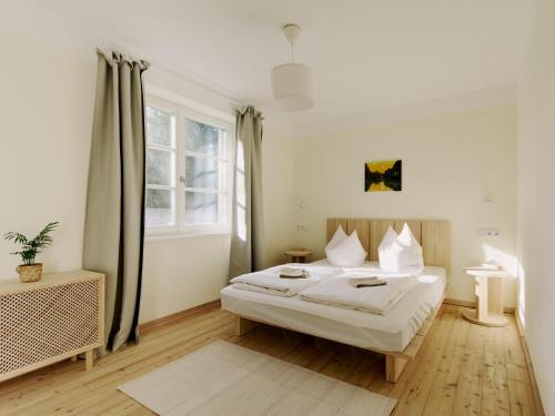 a white bedroom with a bed and a window at Naturhaus Havelland in Rathenow