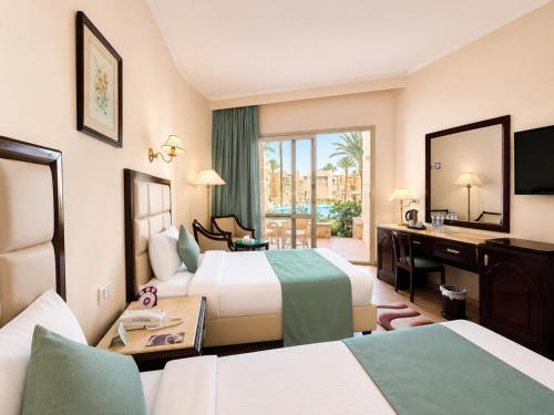 a hotel room with two beds and a desk at Sea Star Beau Rivage Hotel in Hurghada