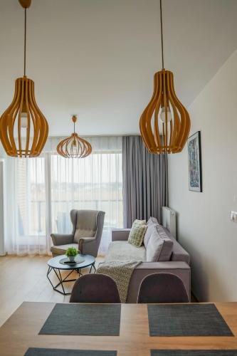 a living room with a couch and two pendant lights at Przystań Apartamenty Sarbinowo in Sarbinowo