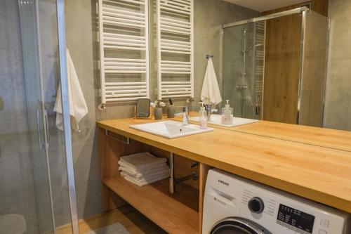 a bathroom with a sink and a washing machine at Przystań Apartamenty Sarbinowo in Sarbinowo