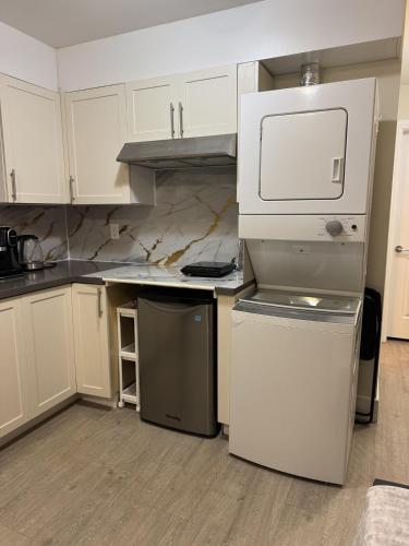 a kitchen with white cabinets and a white refrigerator at Garden suite in Vancouver
