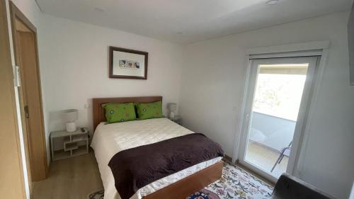 ein Schlafzimmer mit einem Bett mit grünen Kissen und einem Fenster in der Unterkunft Quinta do Plaino in Mões