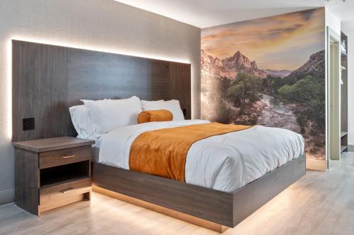 a bedroom with a large bed with a painting on the wall at Zion Promenade Hotel in St. George