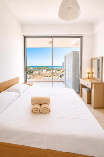 a bedroom with a large white bed with a large window at Best Seaview in Larnaca - 2 BDR Apt - 2 Min Walk to Beach in Larnaca