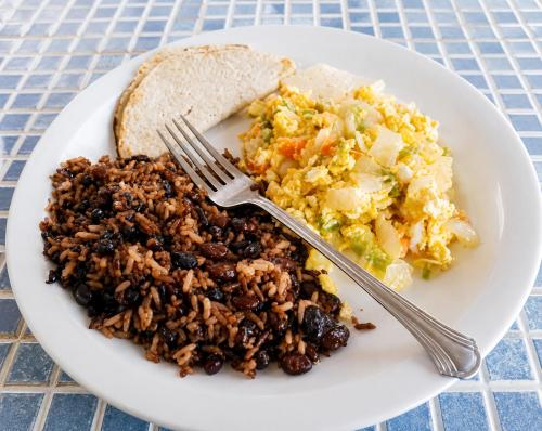 a plate of food with rice and beans and a fork at hotel Oasis Managua Experience - HOME in Managua