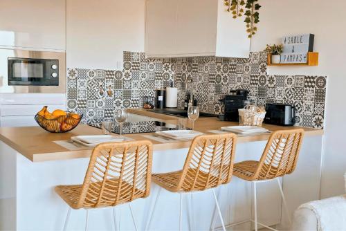 a kitchen with a counter with four chairs and a counter top at Sable & Pampas - Meublé de Tourisme 5 étoiles - Vue Panoramique & Terrasse - Climatisation - Plage à 200m in Carnon-Plage