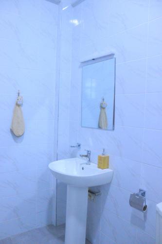 a white bathroom with a sink and a mirror at Polea Hapa Ruaka in Nairobi