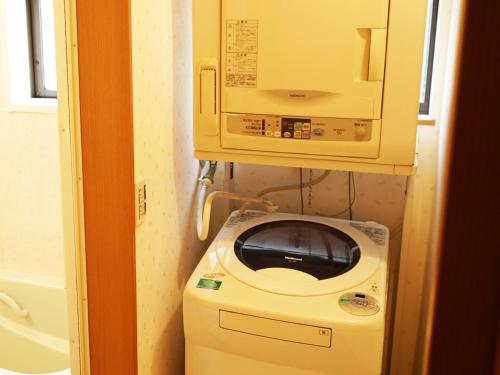 eine Waschmaschine in einem Badezimmer mit einer Mikrowelle in der Unterkunft ECO inn in Inazawa