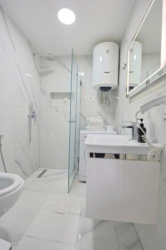 a white bathroom with a sink and a shower at Luxury sea view duplex in Durrës