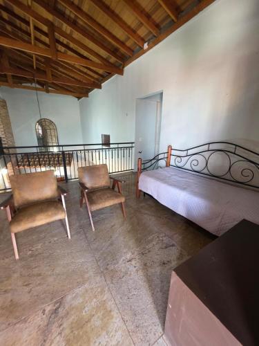a bedroom with a bed and two chairs and a table at Hospedaria 33 in Barretos