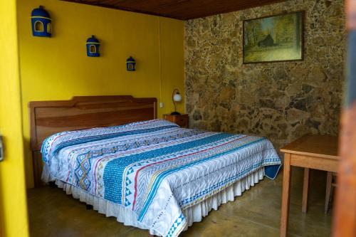 a bedroom with a bed and a stone wall at Hotel Posada La Ermita Cobán in Cobán