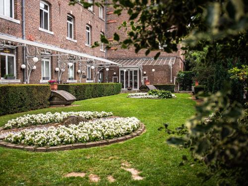 a garden with white flowers in front of a building at Blooma Hotel Liege Centre - Accor Handwritten Collection in Liège