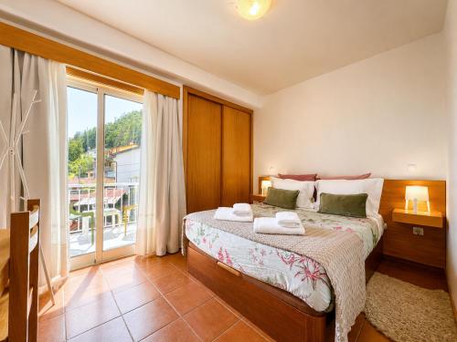 a bedroom with a bed and a large window at Gerês Trail House in Geres
