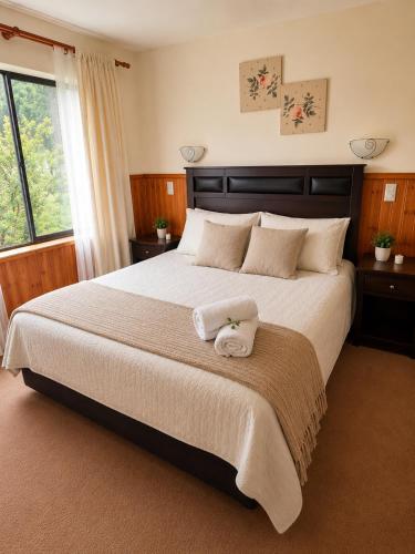 a bedroom with a large bed with two towels on it at Refugio del volcán in Pucón