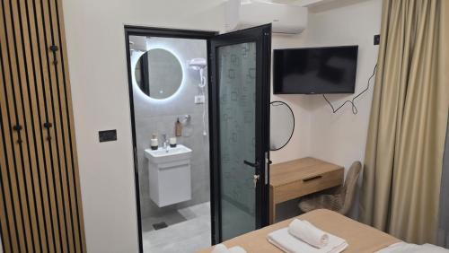 a bathroom with a shower with a sink and a mirror at Kamel Rooms & Apartments in Bijelo Polje