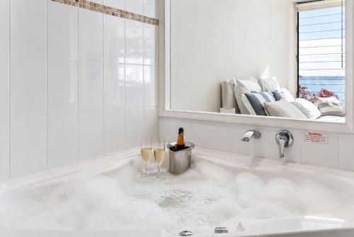 a bath tub with two glasses of wine in it at Mirage 1 24 Gloucester Street in Nelson Bay