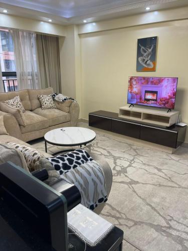 a living room with couches and a flat screen tv at Kaisa garden in Nairobi