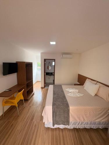 a bedroom with a bed and a desk and a television at Pousada O Sol De Maragogi in Maragogi