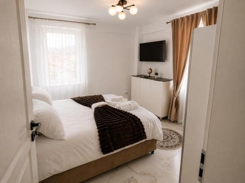 a bedroom with a bed with white sheets and a window at Zori de Bucovina Apartament in Gura Humorului